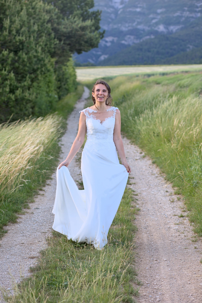 Promenade bohème dans les champs Photo prise durant la fin de la séance couple. La mariée déambule avec le sourire et joie dans un champ durant le coucher de soleil. Une photo prise en fin de journée, après le stress des cérémonies.
