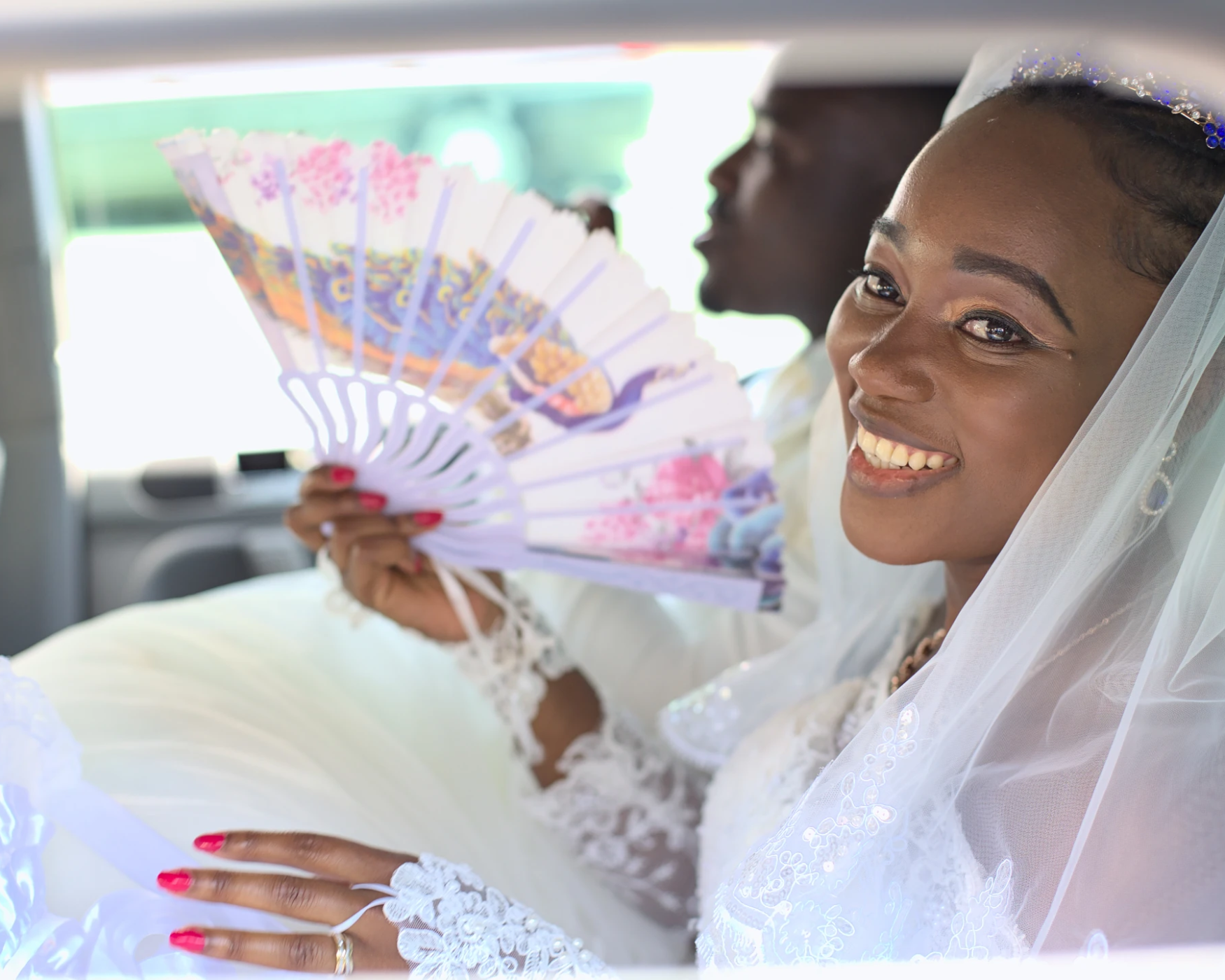 En route vers la cérémonie de mariage ! Photo de la mariée prise à travers la fenêtre de la voiture, juste avant la cérémonie religieuse. La mariée est tout sourire.
