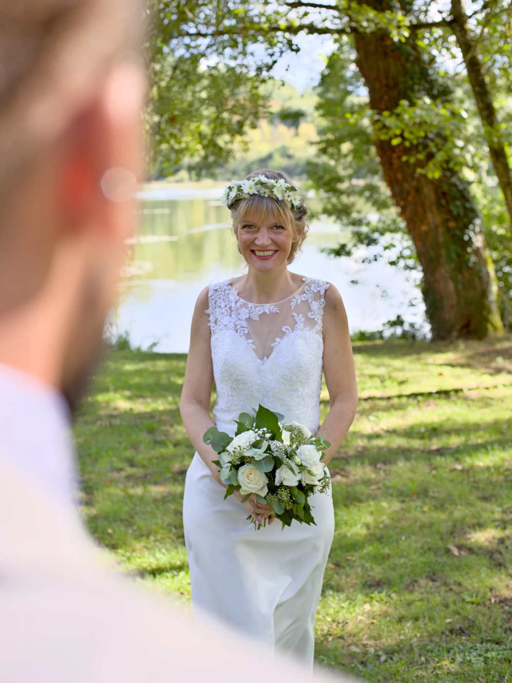 La mariée qui rejoint son époux La mariée rejoins le marié avec bouquet de fleurs à la main. Photo prise durant la séance couple de mariage dans un cadre naturel et près d'un lac.